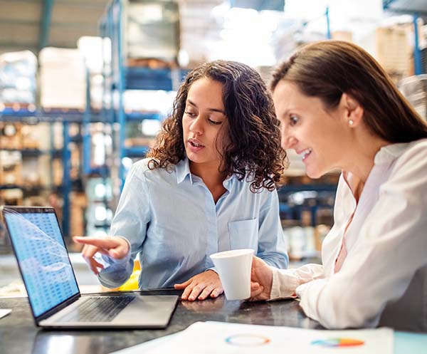 women working in warehouse on laptop
